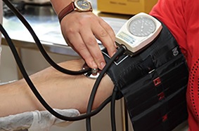 A patient is shown wearing a blood pressure monitor.
