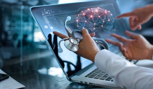 hands holding stethoscope in front of computer