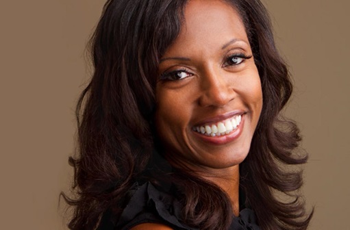African American woman smiling in front of brown background