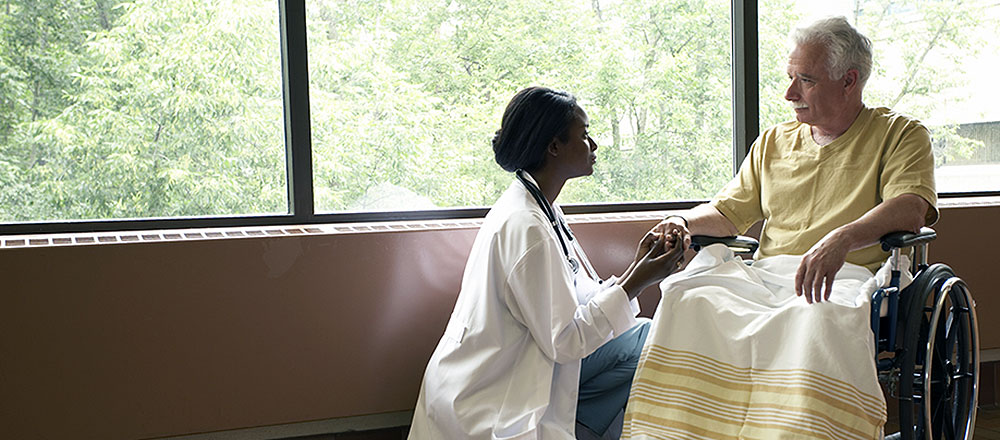 Doctor comforting elderly man in a wheelchair
